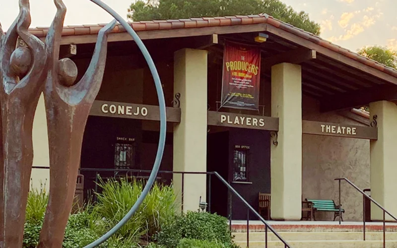 Front entrance of Conejo Players Theatre in Thousand Oaks, California, featuring the iconic bronze sculpture and the theater sign above the doors.