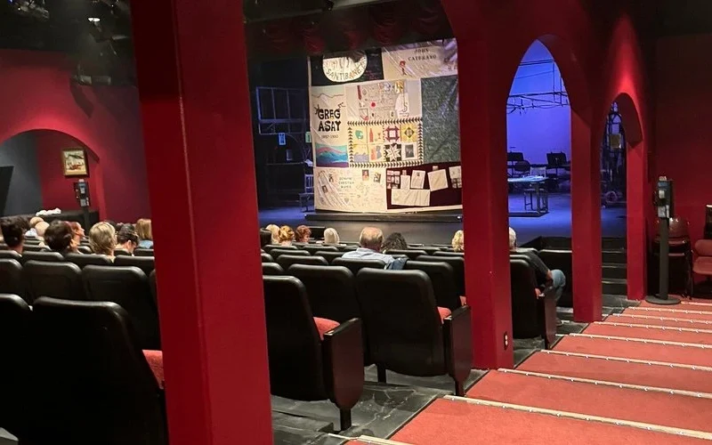 Audience seated inside Conejo Players Theatre, looking toward the stage with red arches and soft lighting before a live performance.