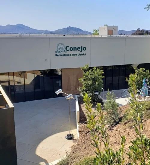 Exterior view of the Conejo Recreation & Park District building at Hillcrest Center for the Arts in Thousand Oaks, surrounded by hillside plants and mountain views.