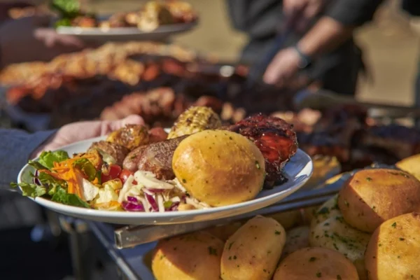 Plate of barbecue with ribs, grilled corn, salad, and fresh rolls served at Wood Ranch BBQ & Grill in Agoura Hills