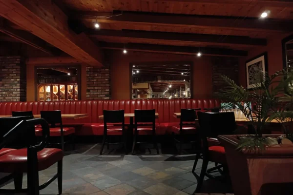 Interior of Wood Ranch BBQ & Grill showing red leather booths, wooden beams, and warm evening lighting