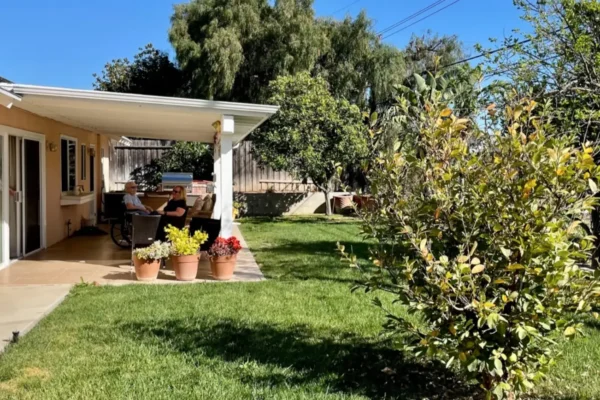 Peaceful backyard patio with residents relaxing under a covered area.