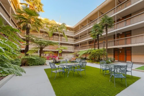 Green courtyard with palm trees and patio tables inside Best Western Plus Thousand Oaks Inn.