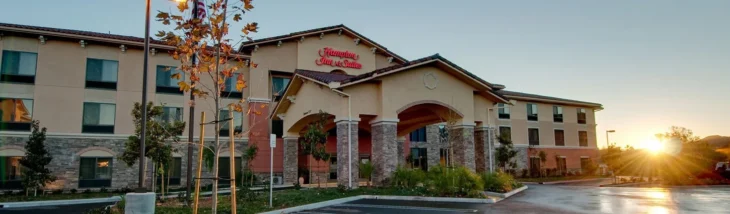 hampton-inn-thousand-oaks-exterior-sunrise Hampton Inn & Suites Thousand Oaks exterior at sunrise with parking area and warm light