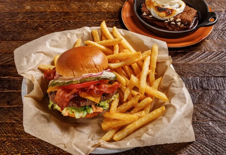 lazydog_thousandoaks_bacon_burger_fries Classic bacon cheeseburger with fries served on rustic wooden table