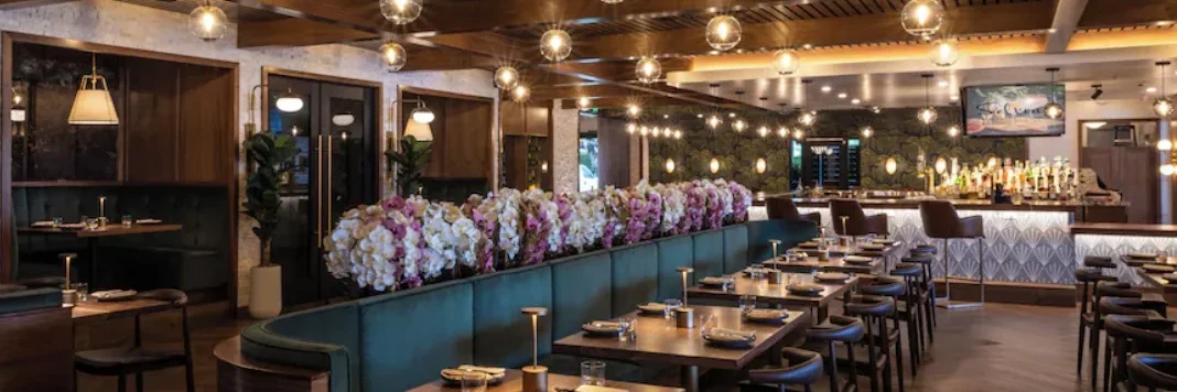 Selvin’s restaurant and bar at Palm Garden Hotel with wood ceiling, teal banquettes and warm pendant lighting