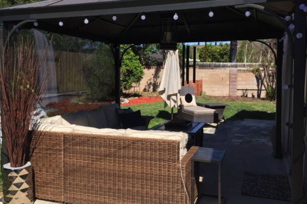 Covered backyard patio at Anita’s Care Villa with outdoor seating, string lights, and a green lawn.