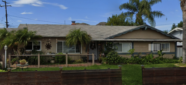 anitas-care-villa-exterior-front-view Front exterior view of Anita’s Care Villa, a single-story home with palm trees, a fenced yard, and a landscaped garden.