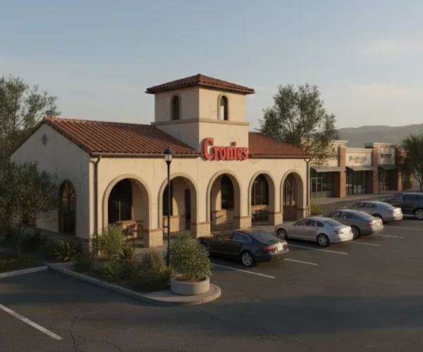 Exterior view of Cronies Sports Grill featuring a Spanish-style beige building with a red tiled roof, arched walkways, and a spacious parking lot.