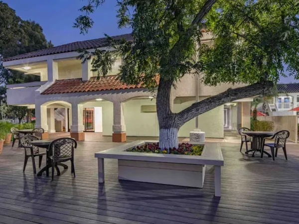 Motel 6 Thousand Oaks courtyard patio at dusk with seating area and large shade tree.