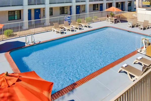 Outdoor pool at Motel 6 Thousand Oaks with sun loungers and orange umbrellas.